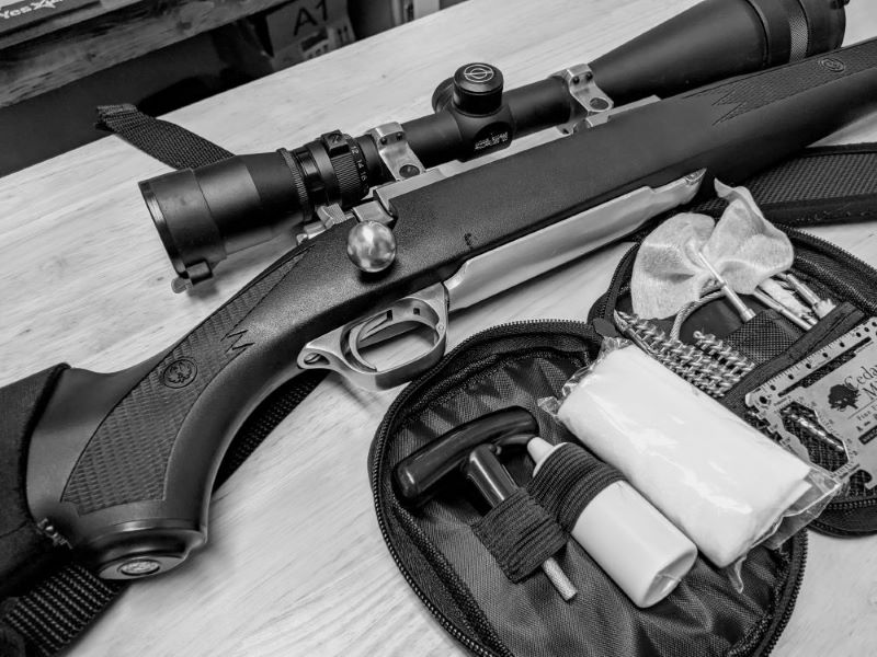 A rifle and Cedar Mill cablesnake rifle cleaning kit on top of a cleaning counter