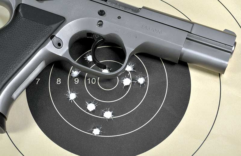 A pistol handgun on a shooting paper target with holes from target shooting