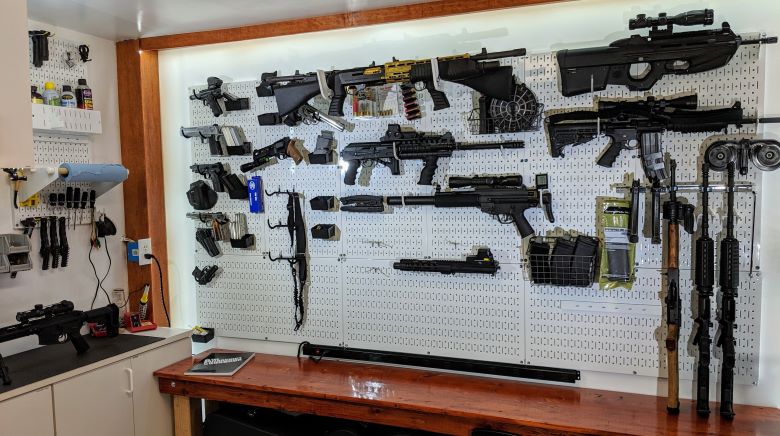 A wall displaying various guns and items arranged for visual impact.