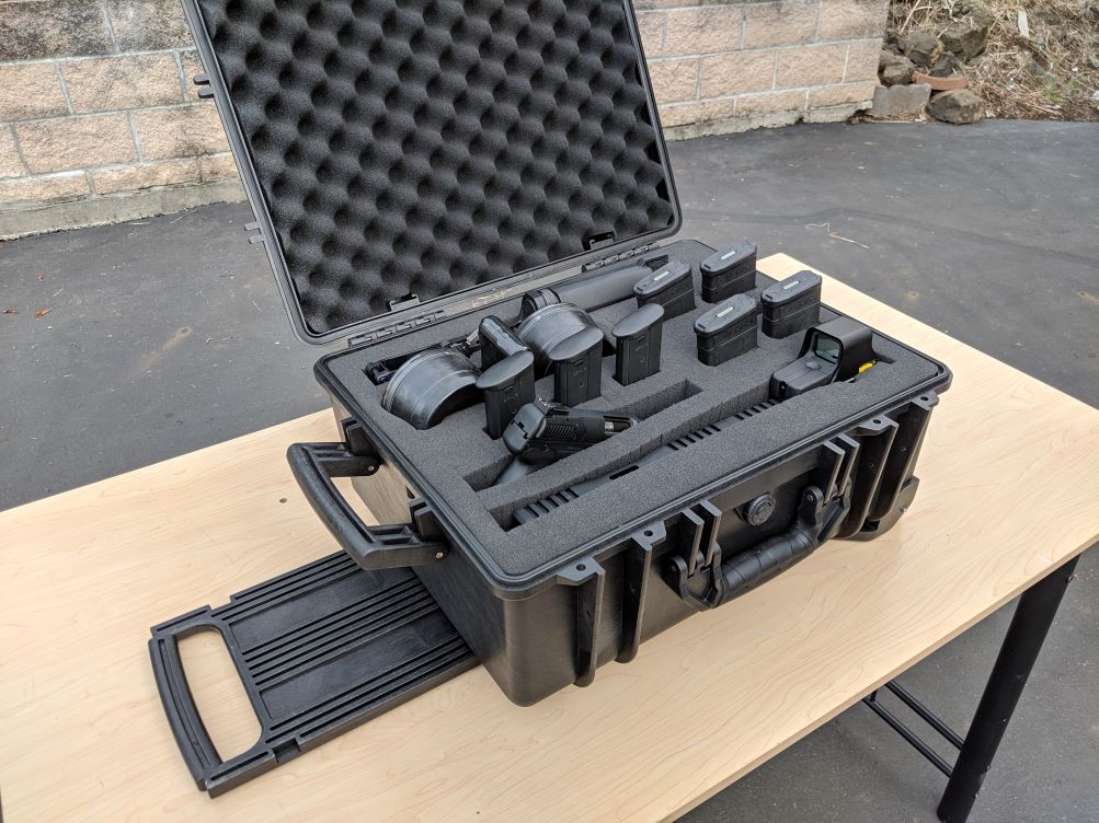 An open black multi-pistol case on a table, displaying different pistols tucked inside the foam insert..